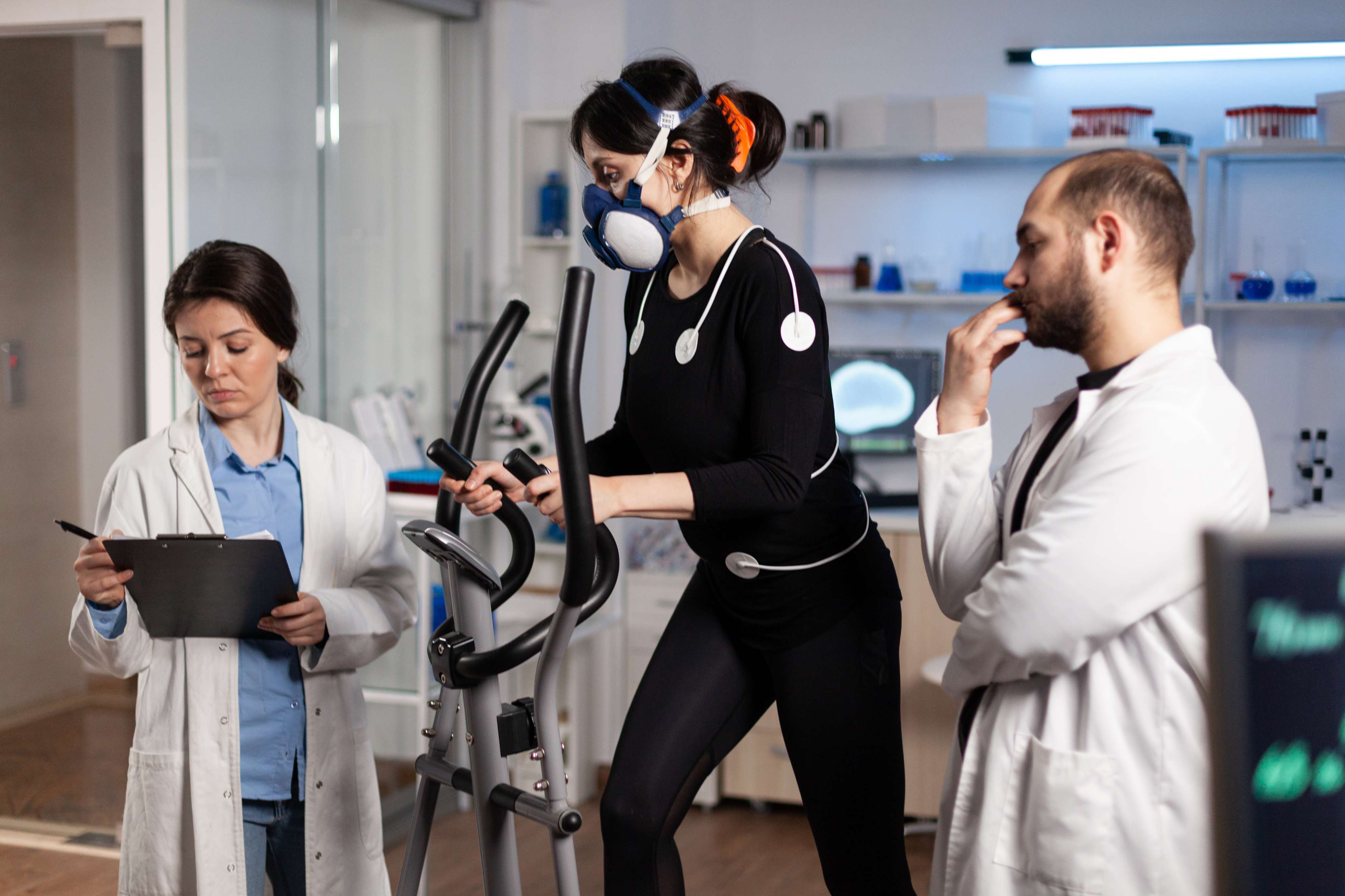 athlete woman with mask running gym bycle trainning body endurance while researcher doctor measuring heart rate monitoring egk data laboratory sportwoman with medical electrodes it at Core Concept