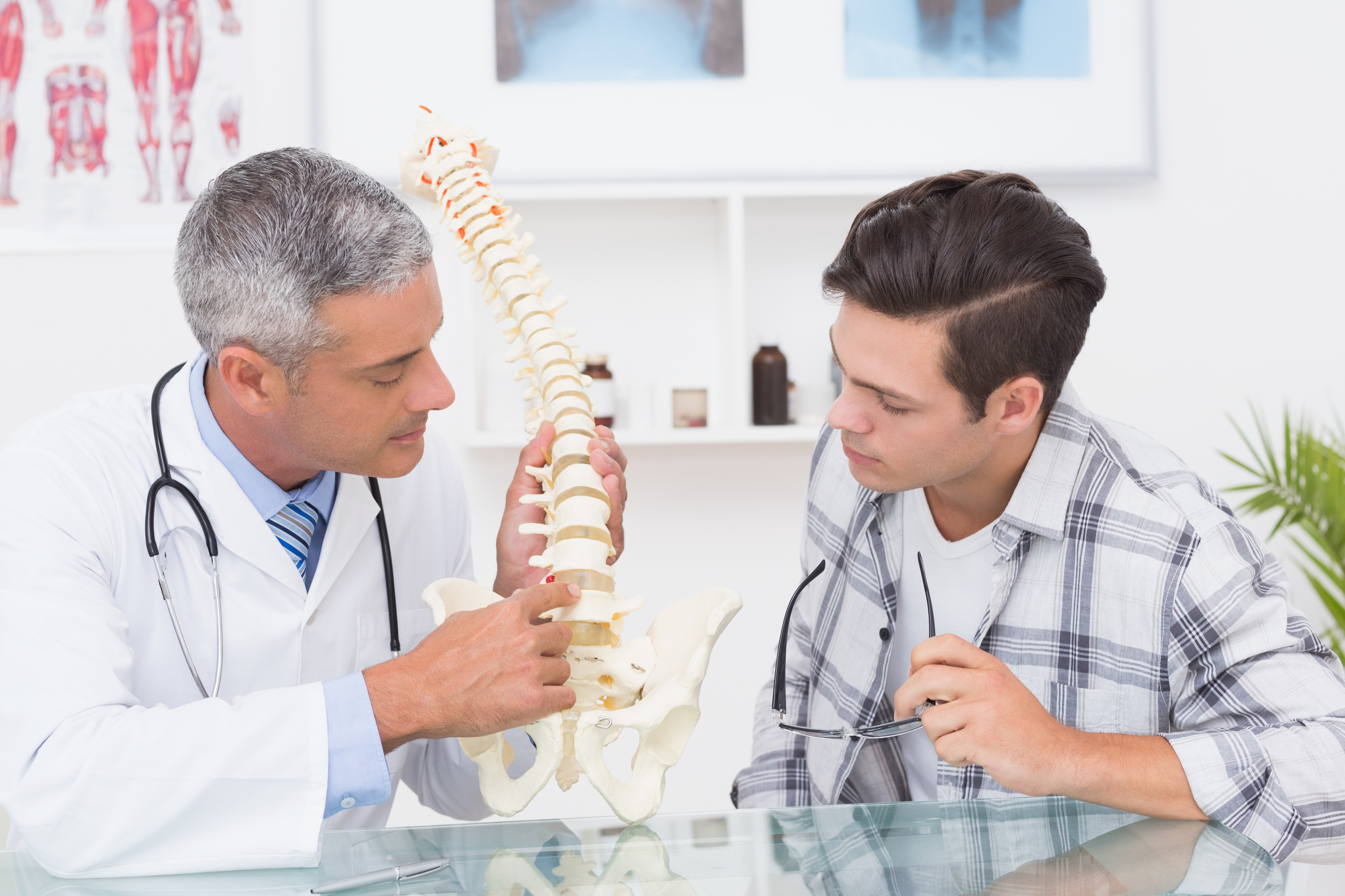 doctor explaining anatomical spine his patient at core concept