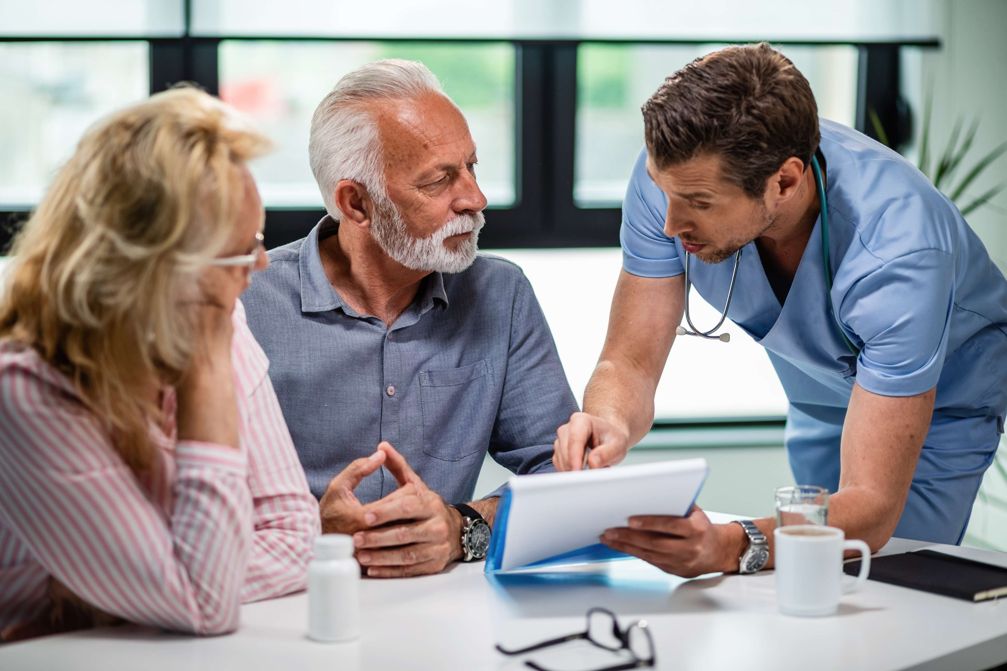 serious doctor discussing with senior couple about their medical documents appointment clinic at Core Concept
