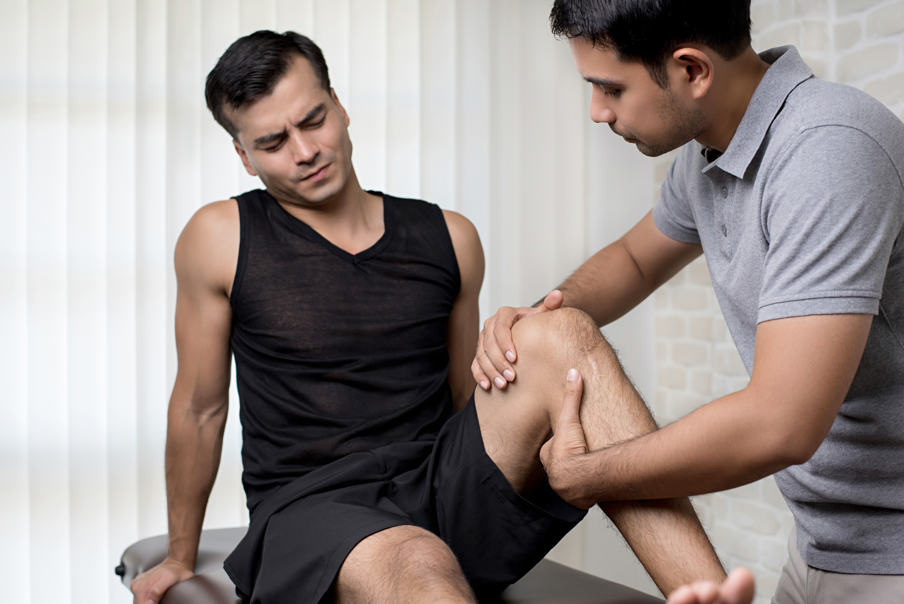 therapist treating injured knee athlete male patient clinic at Core Concept